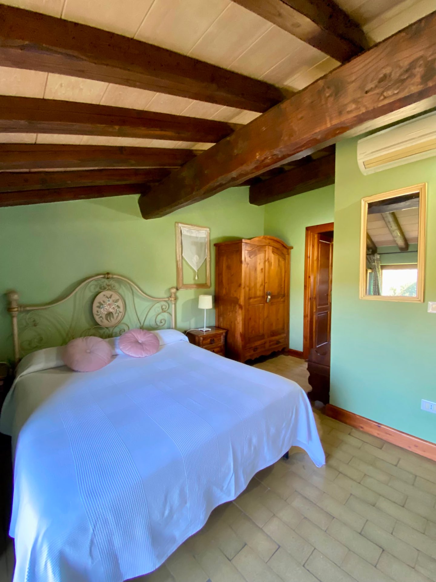 Camera Margherita con letto in ferro battuto, armadio in legno e travi a vista